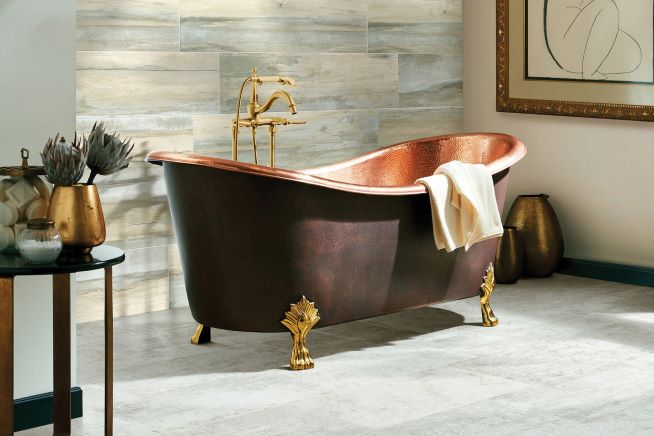 stunning tile flooring in an elegant bathroom with a copper tub and wood look tile accent wall